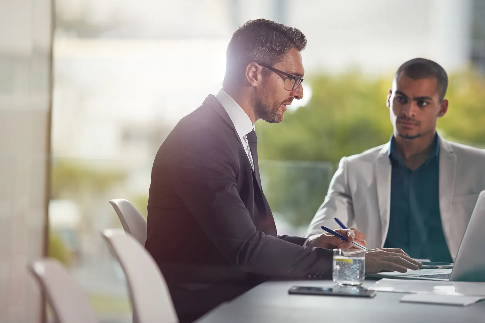 Deux professionnels échangent autour d'une table de réunion avec un ordinateur portable