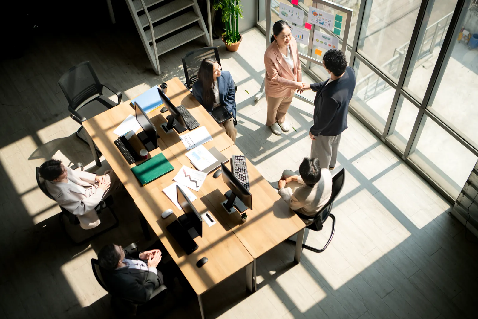 Professionnels dans un bureau lumineux, vus d'en haut, autour d'une grande table