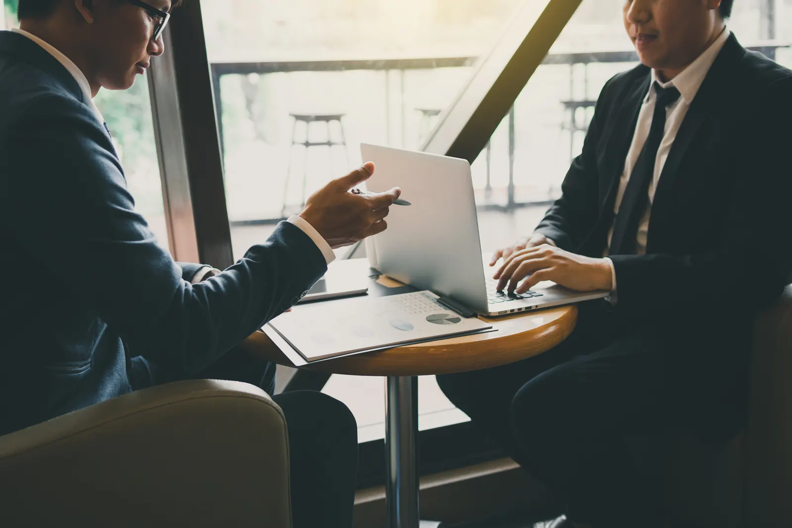 Deux professionnels travaillent sur leurs ordinateurs portables autour d'une table