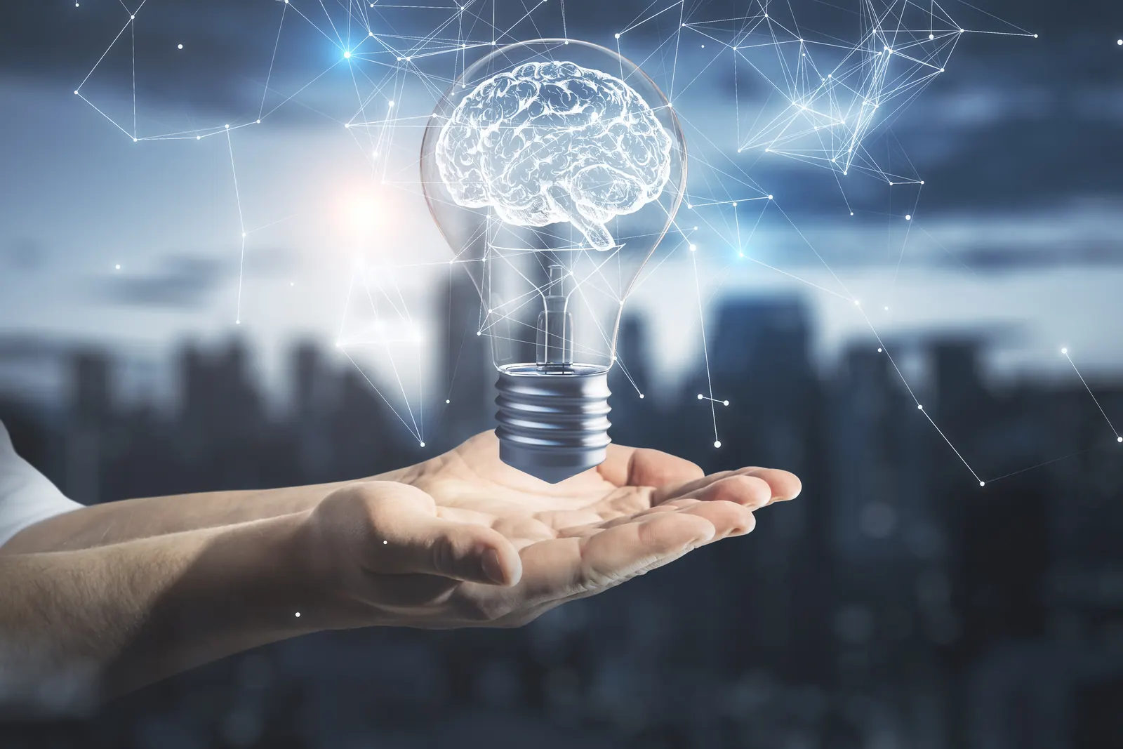 Ampoule lumineuse en forme de cerveau tenue dans une main, devant une ville