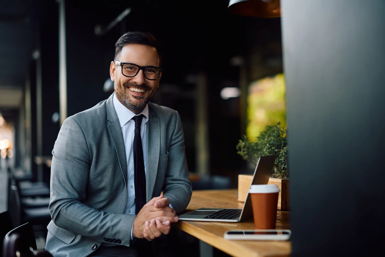 Rédacteur indépendant souriant, ordinateur portable ouvert dans un café